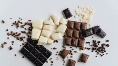 White, milk and dark chocolate pieces on a white background