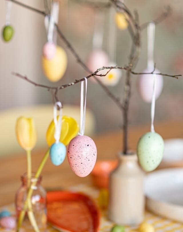painted eggs hanging from branch